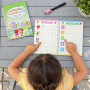 Child tracing numbers in an open reusable workbook, seen from above